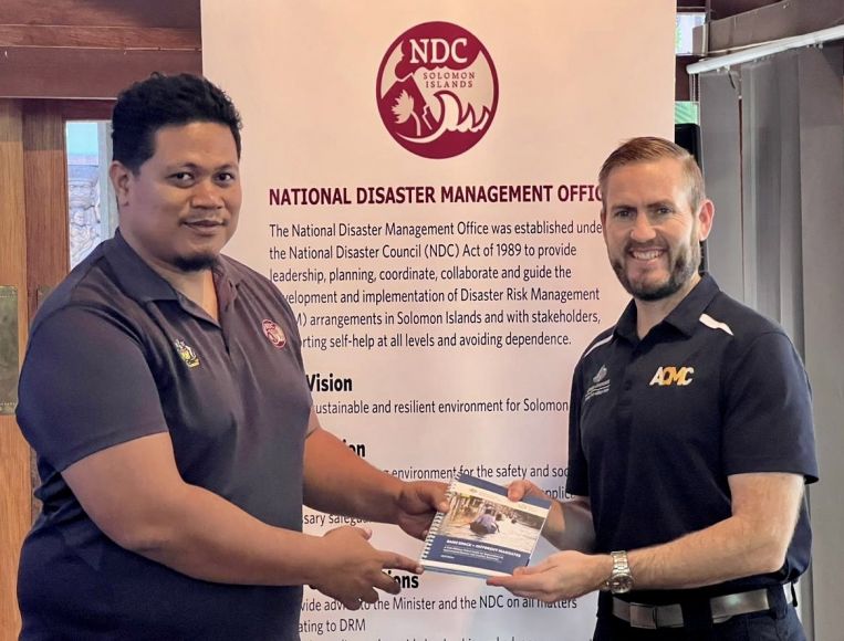 Damian Eaton presents a copy of Same Space – Different Mandates to Director Solomon Islands National Disaster Management Office, Jonathan Tafiariki